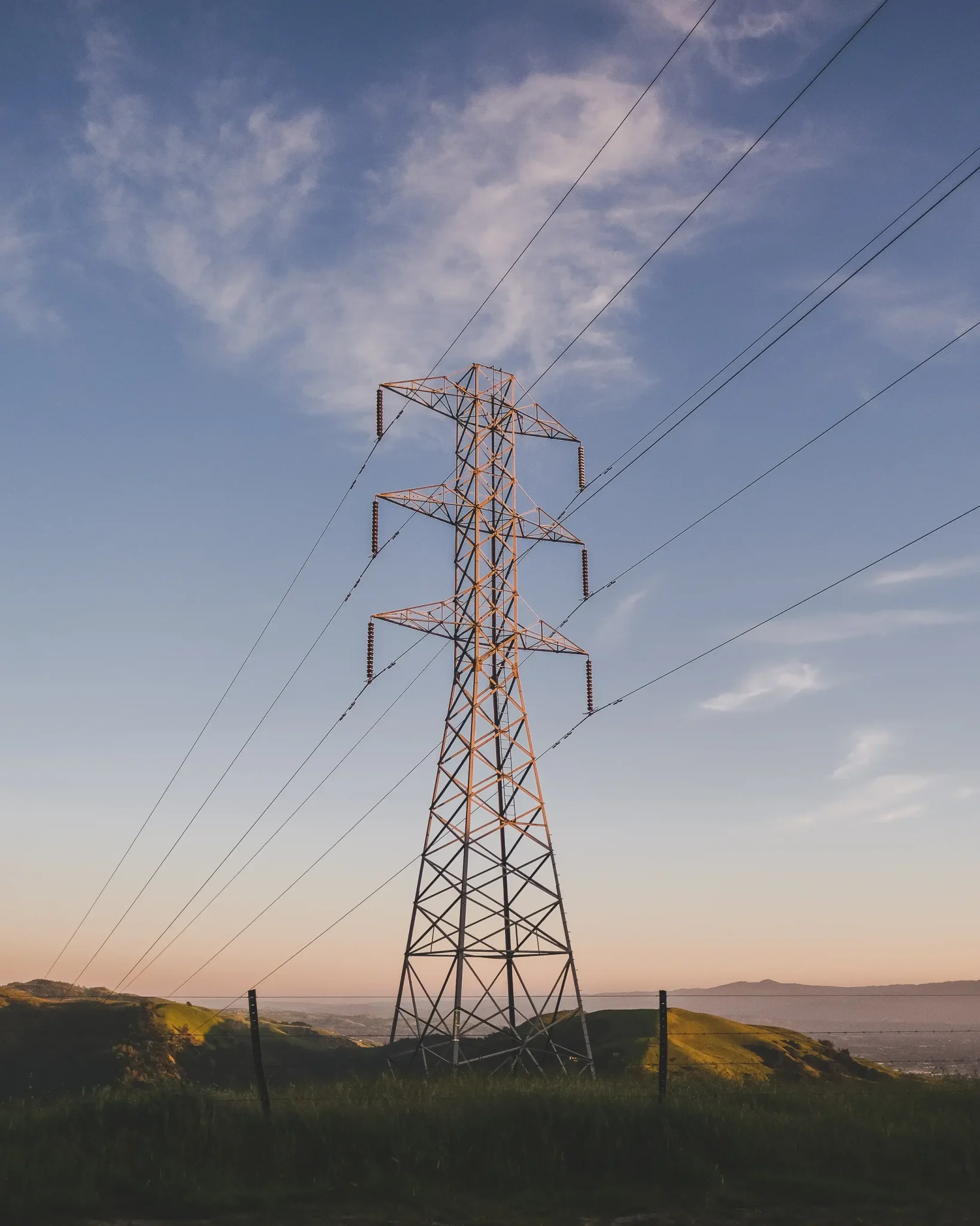 electric tower grassy field blue sky